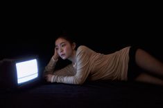 a woman laying on the ground in front of a television