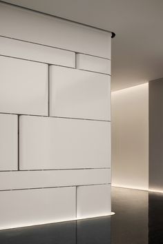 a white brick wall next to a black floor with light coming in from the window