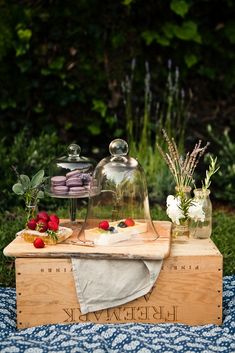 a table topped with cakes and desserts on top of a wooden box