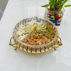 a bowl filled with lots of different types of nuts and almonds next to a potted plant