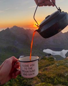 someone pouring coffee into a cup on top of a mountain