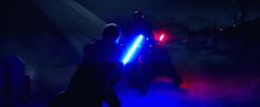 two people standing in the dark with lights on and one person holding a light saber