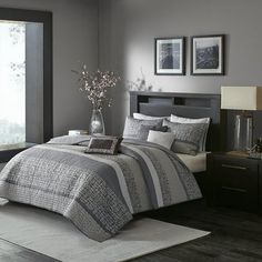 a bedroom with gray walls and bedding in front of a large window that has pictures on the wall