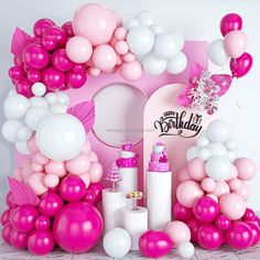 a pink and white birthday party set up with balloons, confetti and decorations