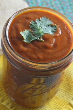 a jar filled with sauce and garnished with cilantro on a yellow napkin