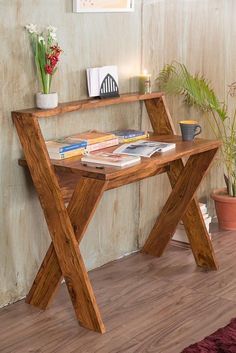 a wooden desk sitting on top of a hard wood floor next to a potted plant