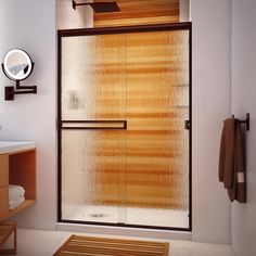 a bathroom with a glass shower door next to a sink and wooden cabinet in it