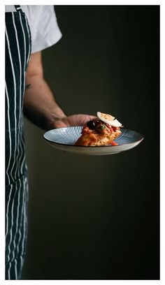 a person holding a plate with food on it in their hand and wearing an apron