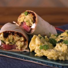 an egg salad burrito and scrambled eggs on a green plate with a blue napkin