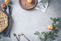 an apple pie on top of a table next to utensils