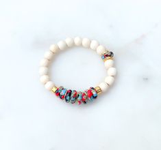 "♥ PLEASE NOTE Runs a little small. I typically wear a size 7 inch bracelet but prefer the 6 3/4 size in this bracelet. Please size accordingly  ♥ THIS BRACELET FEATURES Creamy White Wood 8mm Gold Mykonos Beads 6mm Multicolored Krobo Glass  Brushed Gold Discs ♥ FIND YOUR PERFECT SIZE To size your wrist, wrap a piece of string around your wrist where you want your bracelet to sit. Mark your string with a pen or marker. Use a ruler or measuring tape to measure the marked string. Add 1/2\" to your measurement for a comfortable fit.  Example: If your measurement is 6\", it would be 6.5\" with the added 1/2\". ♥ CARING FOR YOUR BRACELET - Roll bracelets to put on and take off instead of stretching them.  - Make sure your bracelet is store in a cool, dry location.  - Do not wear your bracelet in White Heishi Beads Bohemian Stretch Bracelet, Bohemian White Heishi Beads Stretch Bracelet, White Stretch Bracelet With Round Beads For Festival, Bohemian Heishi Beads Stretch Bracelet As Gift, White Bohemian Beads For Everyday, Everyday White Stretch Bracelet With Large Beads, White Bohemian Stretch Bracelet For Friendship, White Spiritual Friendship Bracelets With Colorful Beads, Wooden And Heishi Beads Bracelets As Gift