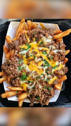 a tray filled with french fries covered in cheese and meat