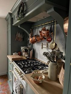 a kitchen with pots and pans hanging on the wall above the stove top, along with other cooking utensils