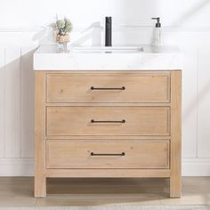 a bathroom vanity with two drawers and a white sink in front of a wall mounted faucet