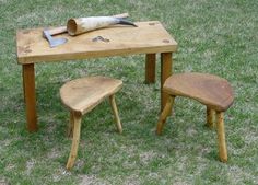 a wooden table and two stools in the grass