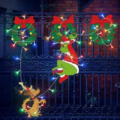 the grinch christmas lights are hanging from a fence with santa's stockings on them