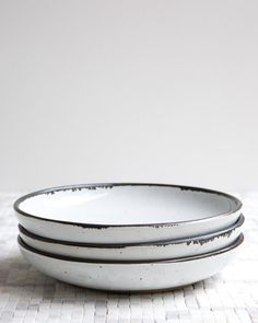 three white plates stacked on top of each other in front of a white wall and floor