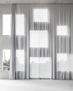 an empty room with white curtains and windows