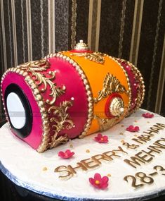 a birthday cake decorated with an orange and pink cylinder on top of a white table