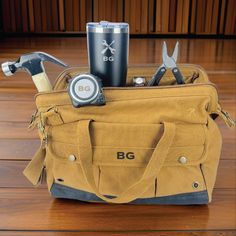 a tool bag sitting on top of a wooden floor next to a cup and wrenches