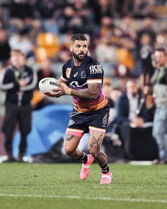 a man running with a rugby ball in his hand and people watching from the stands