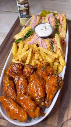 a platter with chicken wings, waffle fries and coleslaw on it