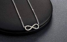 Centered between the two lengths of shiny silver tone chain, this miniature eternity symbol appears to float along the neck. Completely encrusted in micro CZ stones creating incredible shimmer. At only 2 cm this is truly subtle and graceful. This necklace is perfect for women, teens or young children. Length: 18 inch chain Stones: CZ Metal: Sterling Silver, 3 layers of platinum plating. Comes in a gift box. (Reg $45.99) Infinity Necklace With Diamond Accents In Cubic Zirconia, Cubic Zirconia Infinity Necklace With Diamond Accents, Infinity Shaped Cubic Zirconia Necklace With Diamond Accents, White Gold Infinity Jewelry With Cubic Zirconia, White Gold Infinity Necklace With Cubic Zirconia, White Gold Infinity Cubic Zirconia Jewelry, Silver Infinity Clavicle Chain Jewelry, Silver Infinity Clavicle Chain Necklace, Silver Infinity Jewelry With Adjustable Chain