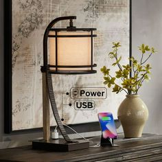 a table lamp sitting on top of a wooden desk next to a vase with flowers