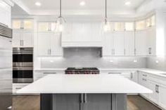 a large kitchen with white cabinets and stainless steel appliances