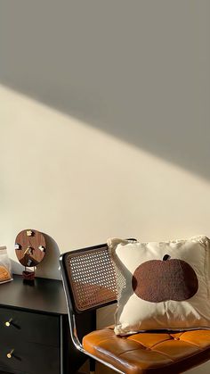 a brown leather chair sitting next to a black table with a white pillow on it