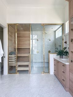 a walk in shower sitting inside of a bathroom next to a white sink and wooden cabinets