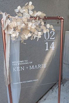 a wedding sign with flowers on it next to a wall and steps in front of a building