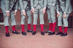 a group of men in suits and red socks standing next to each other with their hands on their hips