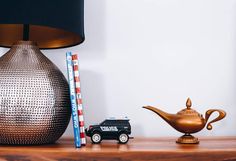 a table with a lamp, toy cars and a teapot on it