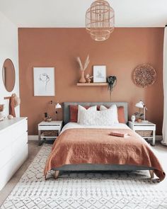 an orange and white bedroom with a bed, dressers, lamps and pictures on the wall