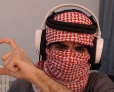 a man wearing headphones and a bandana pointing at the camera with his finger