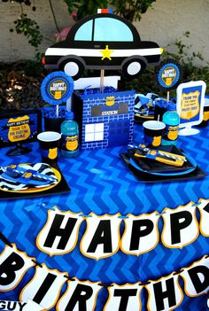 a blue table topped with plates and cups filled with cake next to a sign that says happy birthday