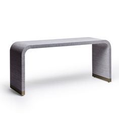 a modern console table in grey fabric with gold accents on the top and bottom, against a white background