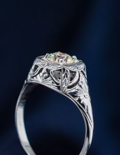 an antique style diamond ring with filigrees on the sides and center stone