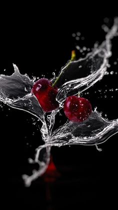 two cherries are splashing into water on a black background with red and white accents