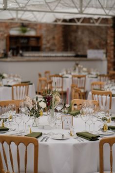 Tablescape complete with green fabric napkins and white tablecloths with vases filled with small floral bouquets Green Wedding Napkins Table Settings, Round Table White Tablecloth, Wedding Table Tablecloth, Simple Centrepiece Wedding Round Table, Whimsical Wedding Round Table, Wild Flower Round Table, Round Table Minimalist Wedding, Simply Wedding Table Decor, Round Table Dinner Setting