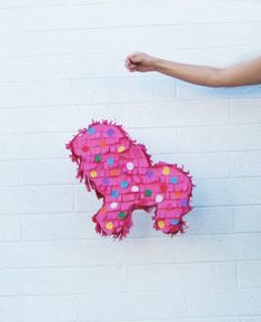 a pink horse made out of donuts on the side of a white brick wall