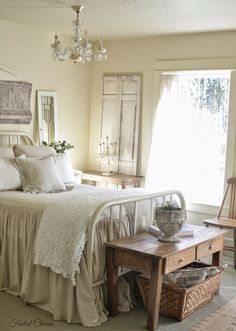 a white bed sitting next to a window in a room with lots of pillows and blankets on top of it