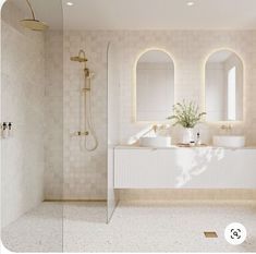 a bathroom with two sinks, mirrors and a shower head mounted to the side of the wall