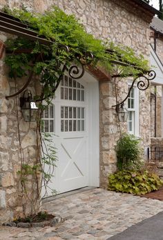 a stone house with vines growing on the front door and side windows, along with a brick walkway