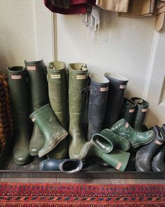 several pairs of rain boots are lined up on the floor in front of a door