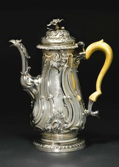 a silver tea pot with a yellow handle