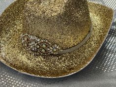 This is a gorgeous gold glitter cowboy hat adorned with a rhinestone band and gold and rhinestone center. Great for music festival or bachelorette party.  Hand decorated so no two are alike. Glitter has been sealed to help prevent shedding. Party hat. Message if you have any questions or would like to have your hat personalized. Glitter will not shed off. Gold Western Fedora Hat, Gold Fedora Western Hat, Western Gold Hat Bands For Party, Western Style Gold Hat Bands For Parties, Gold Hat Band For Party With Curved Brim, Gold Curved Brim Hat Band For Party, Gold Western Hat Band For Kentucky Derby, Western Gold Hat Bands For Kentucky Derby, Gold Fedora Hat For Rodeo