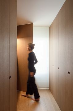 a blurry photo of a person walking down a hallway with wooden cabinets on both sides