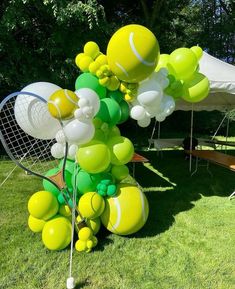 a bunch of balloons are in the shape of tennis balls and racquets